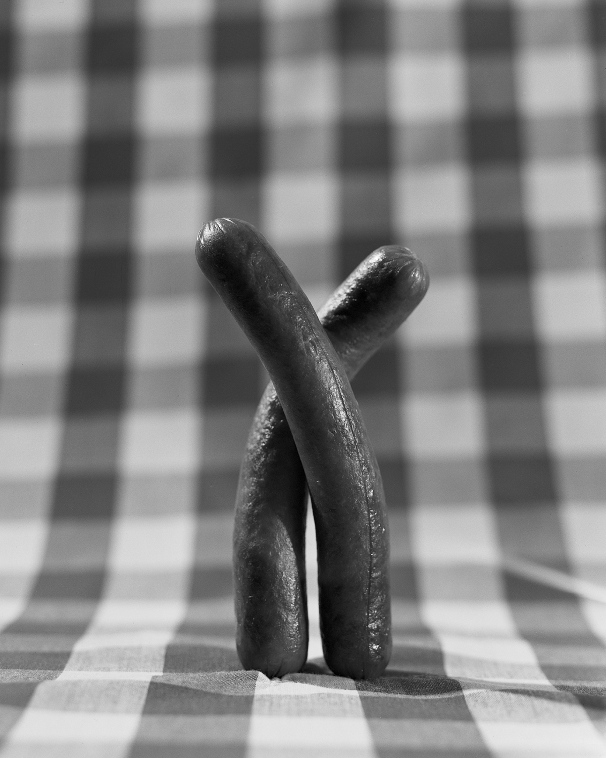 Two hot dogs wrapped around each other in an embrace.
